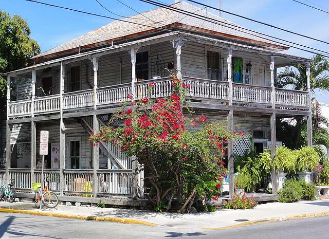 A restored two-story wood-frame house with a wraparound porch in a historic district