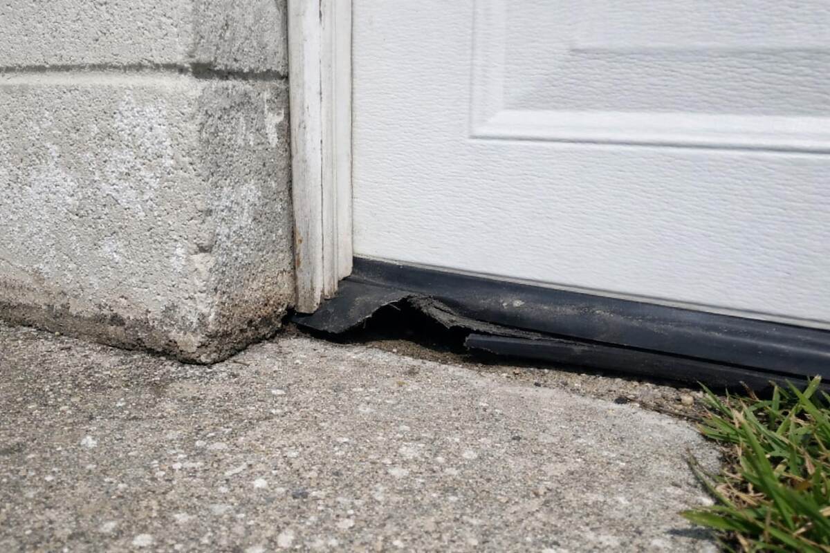 The bottom corner of a garage door and its rubber seal