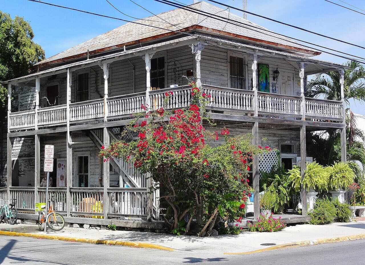 A restored two-story wood-frame house with a wraparound porch in a historic district