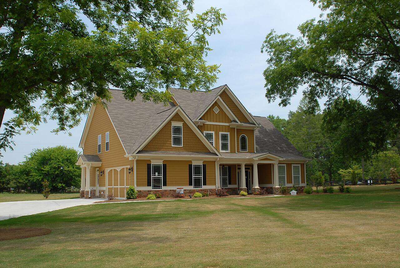 A wood-frame farmhouse on open land with outbuildings